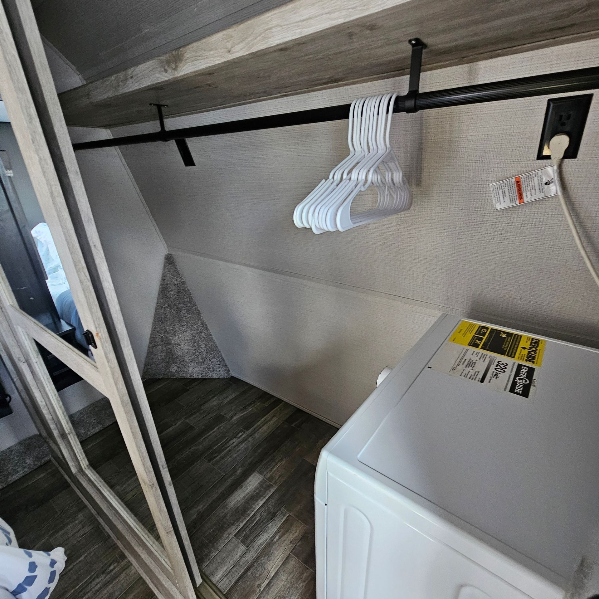Closet with clothes rod and hangers, a washer, and an electrical outlet in an RV