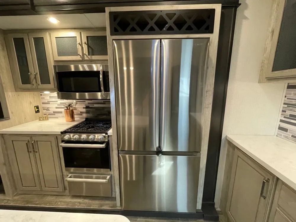Kitchen in RV with stainless steel refrigerator, cabinets, stove, and microwave