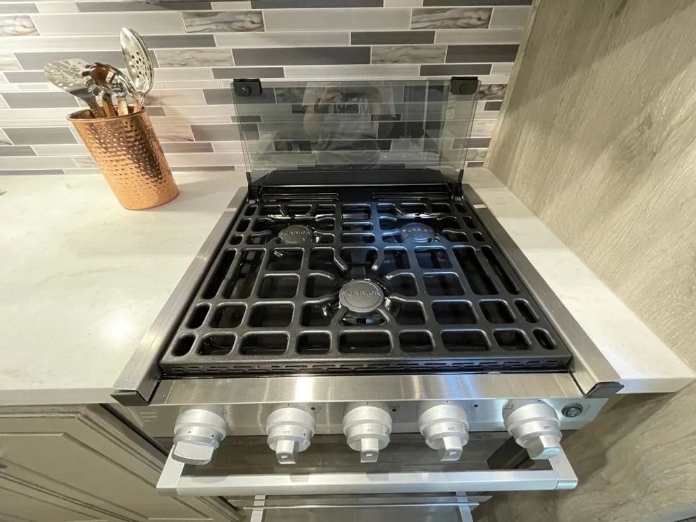 Gas stovetop with a glass cover, in a kitchen with a mosaic backsplash