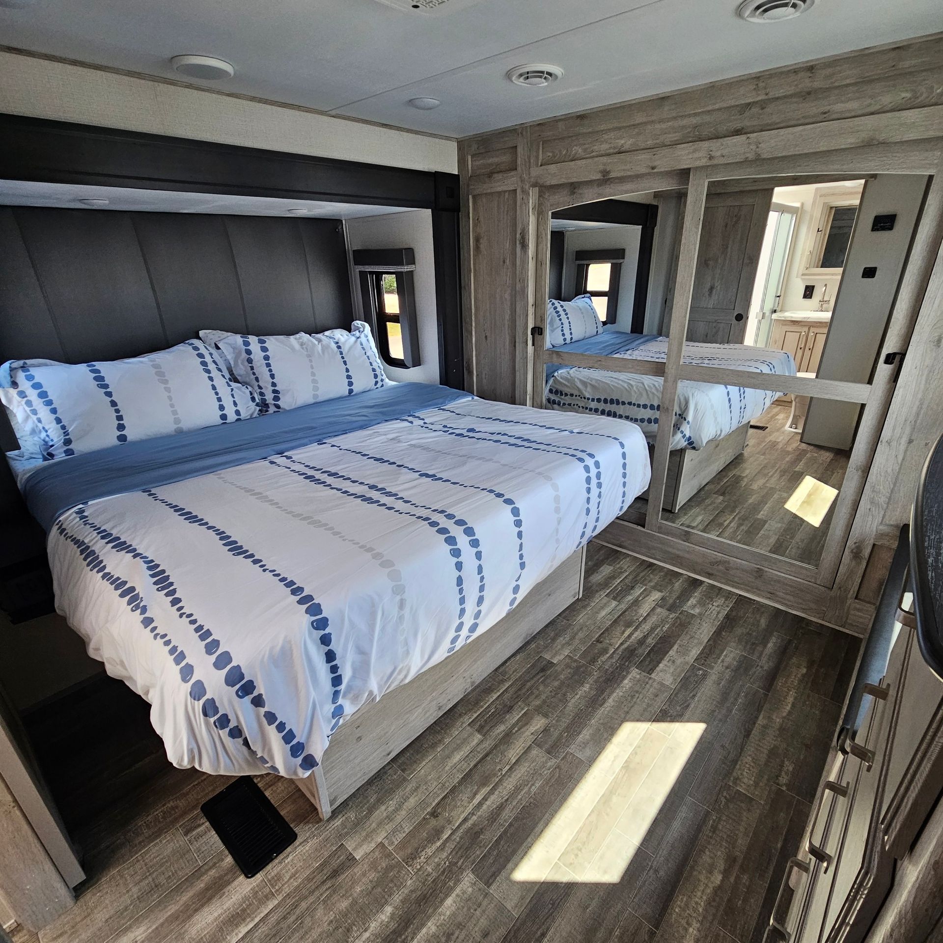 A bedroom in a RV with a large bed and mirrors