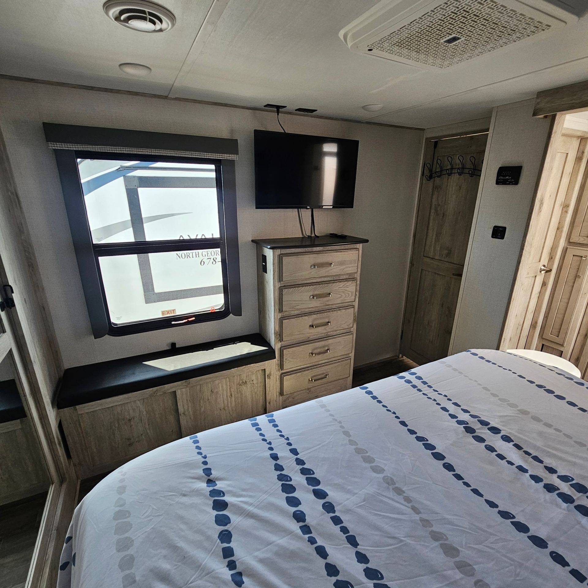 A bedroom with a bed, dresser, television and window