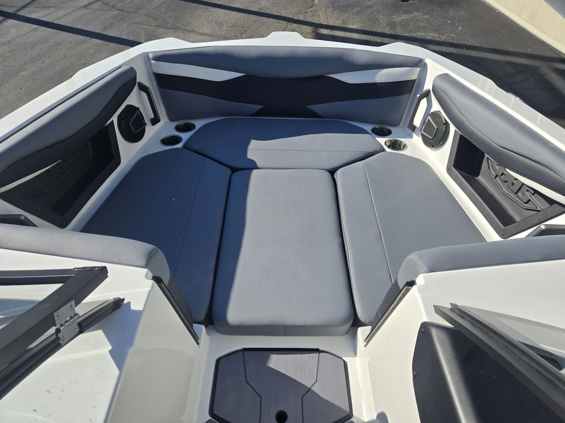 The front of a boat with gray seats and speakers