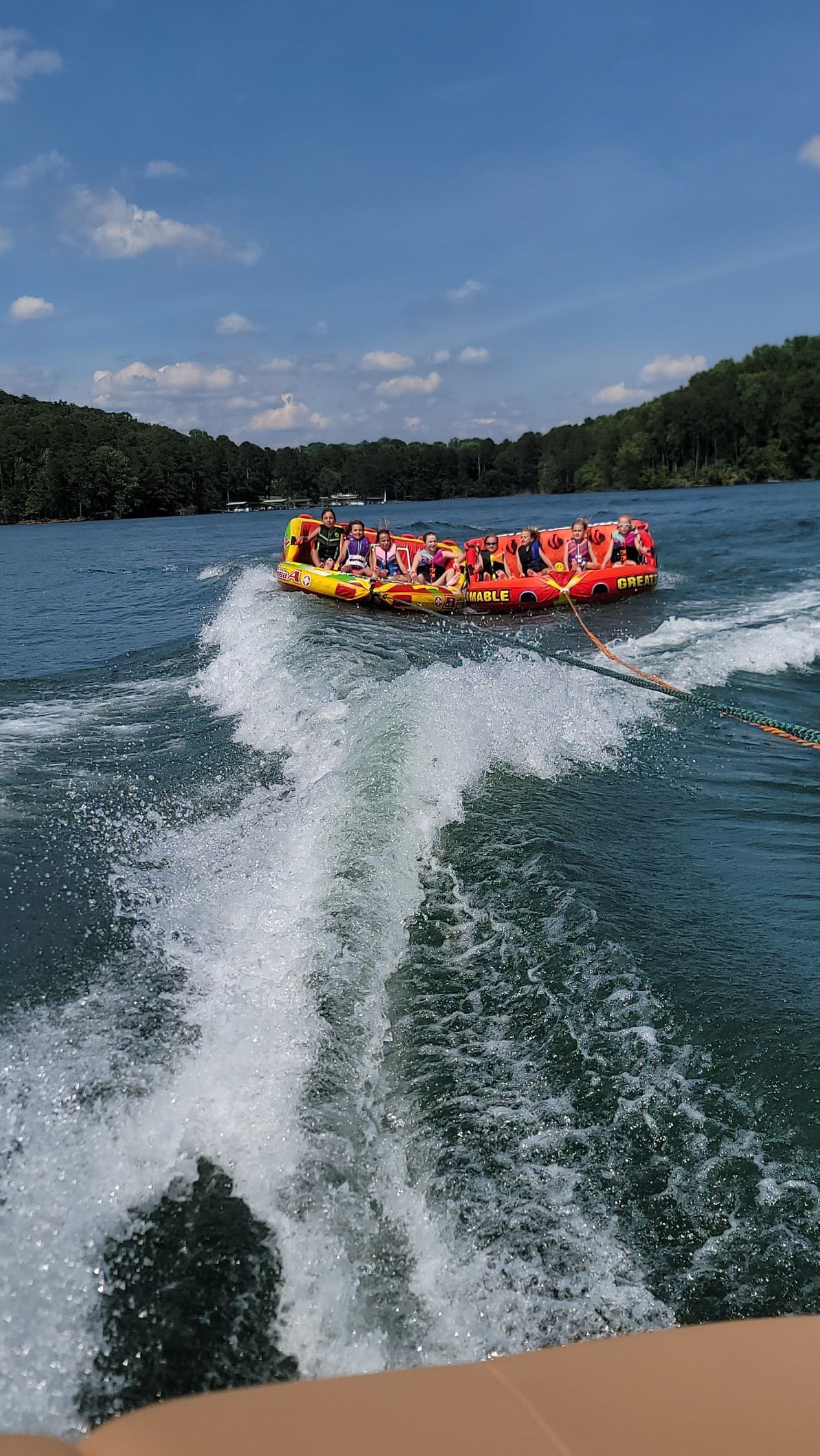 A group of people are sitting on the back of a boat on a lake.
