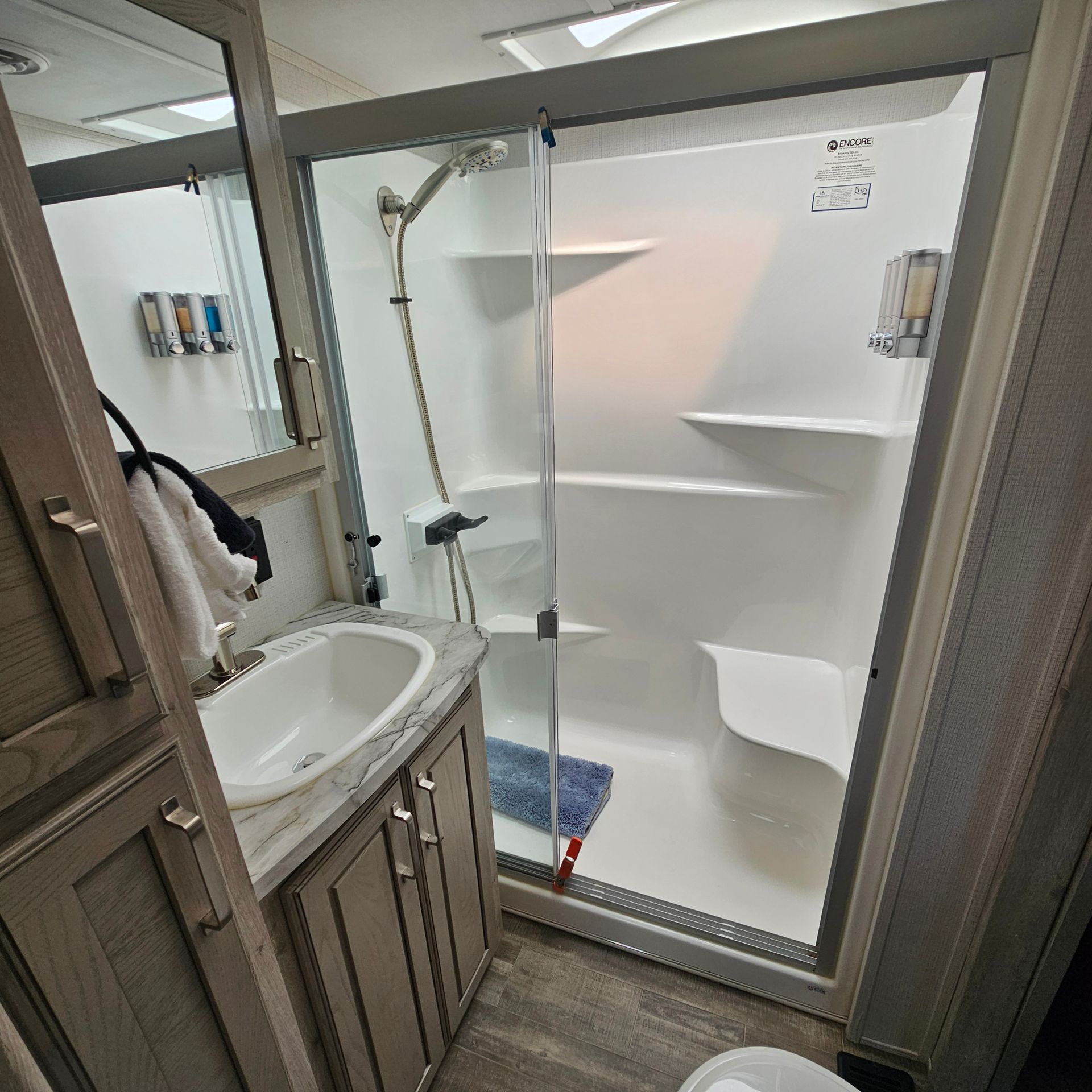 A bathroom with a sink, toilet, shower and mirror