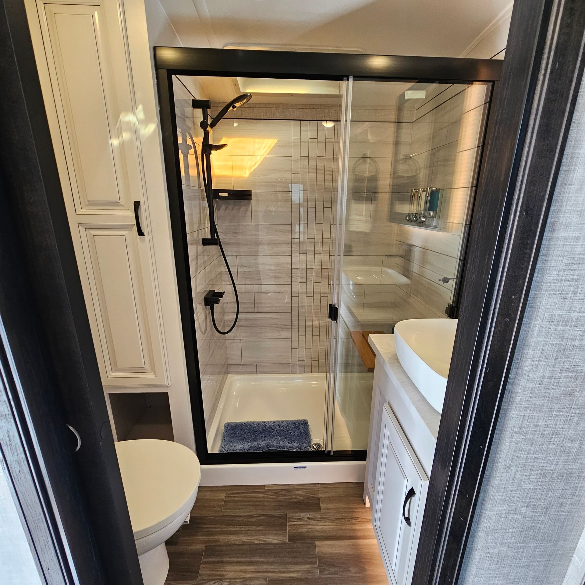 RV bathroom with a shower, toilet, sink, and cabinets