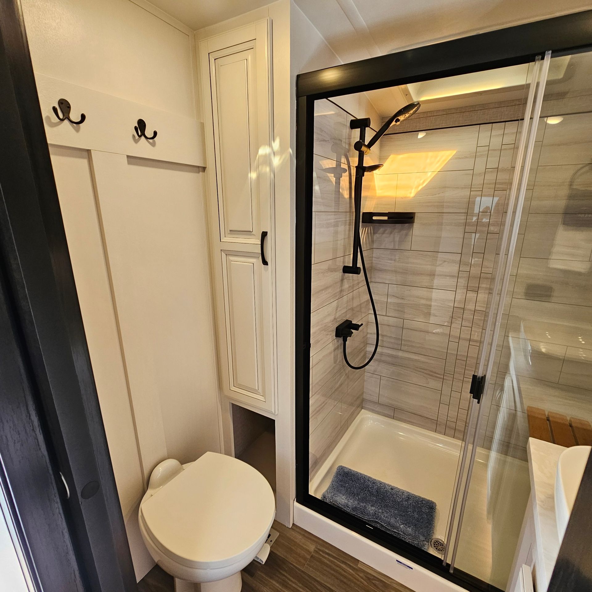 Bathroom in a RV with a toilet, shower, and storage cabinet