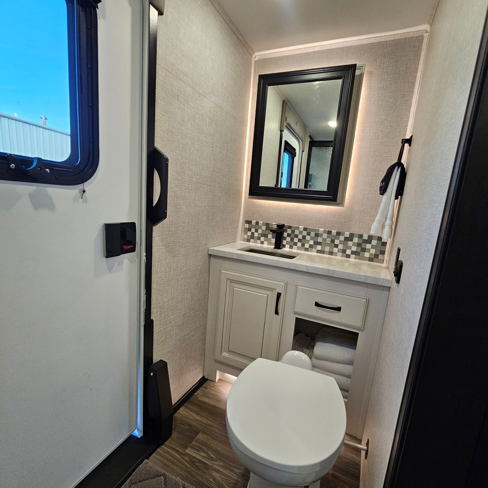 Small RV bathroom with a toilet, sink, and mirror