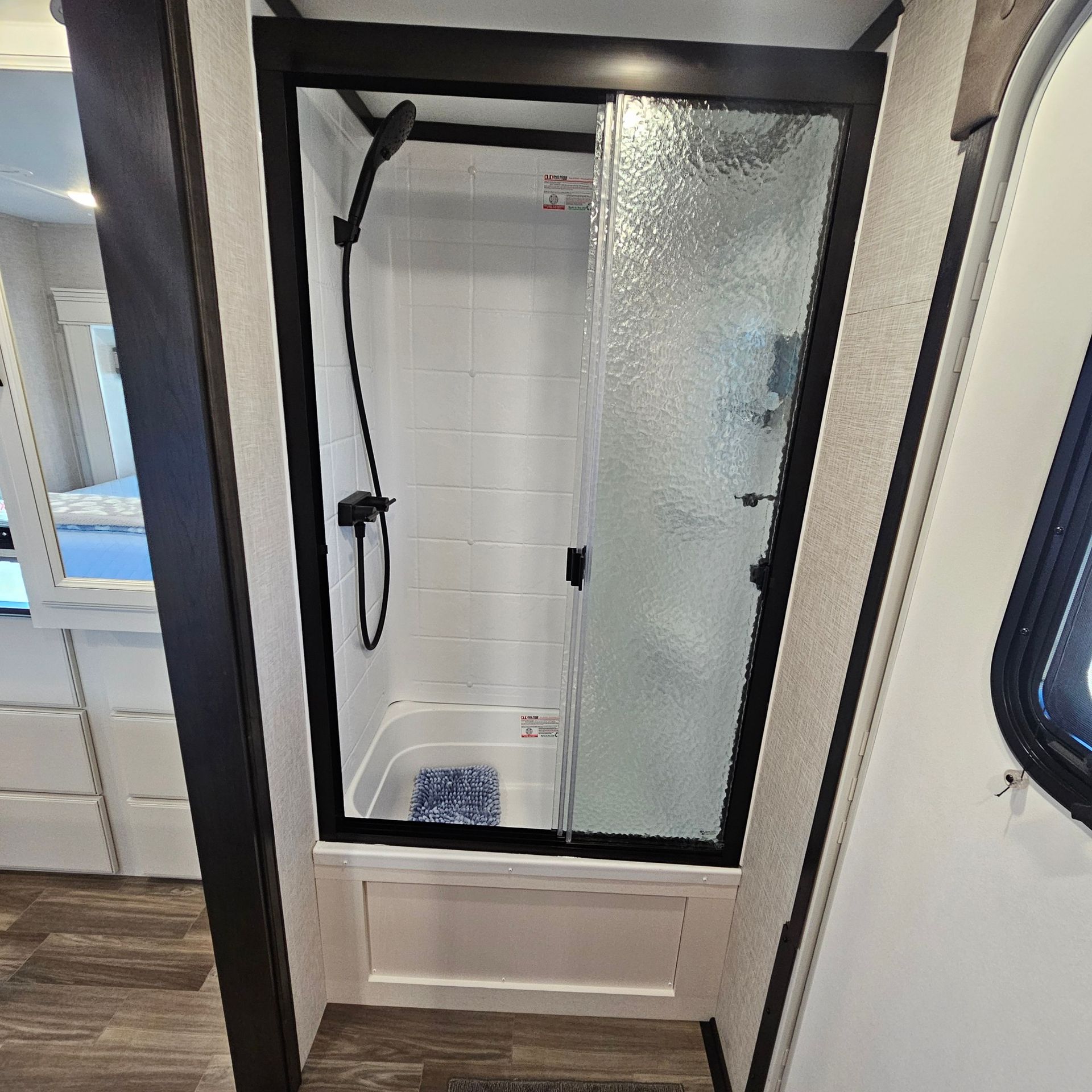 RV shower with black frame, glass door, and black showerhead