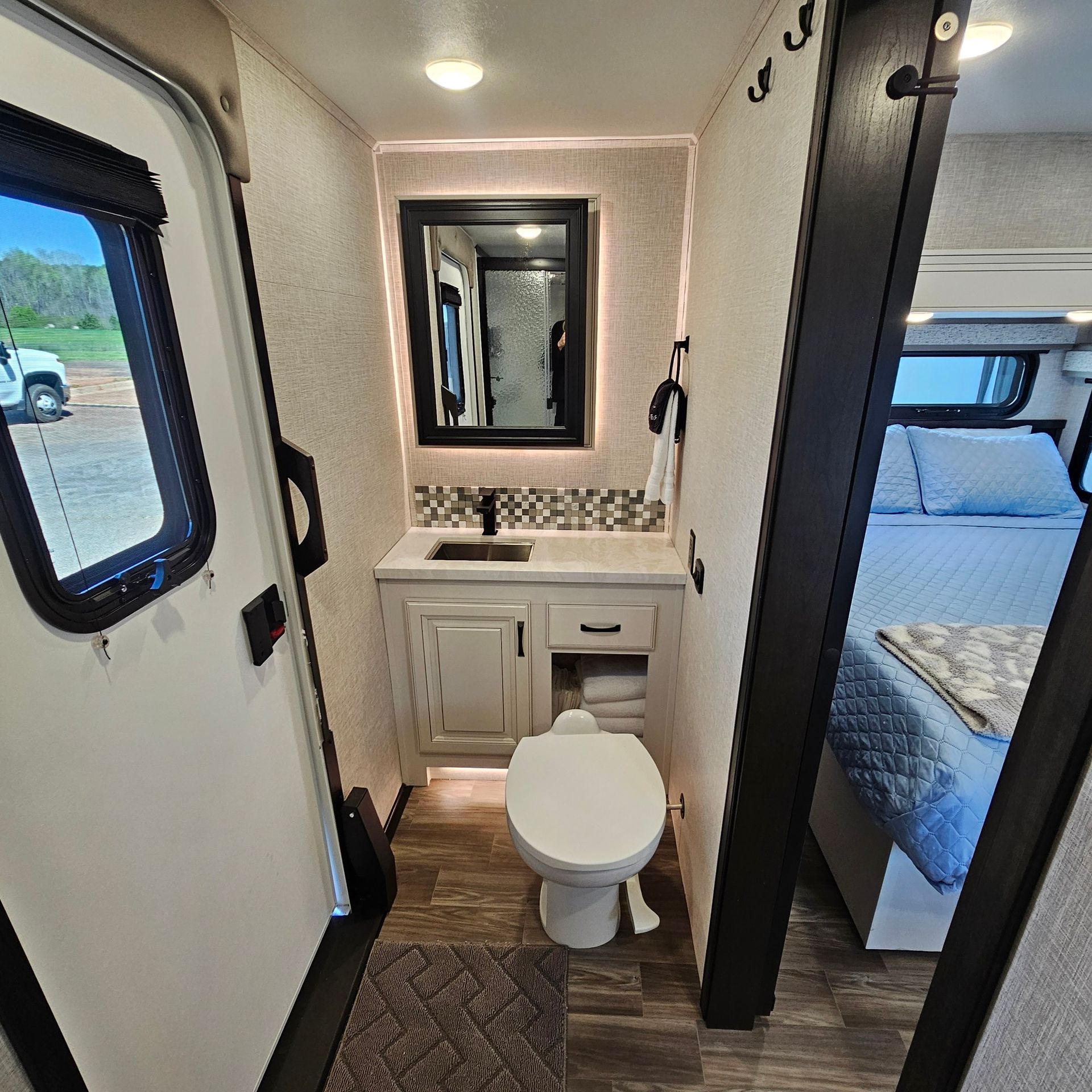 Bathroom in an RV with a toilet, sink, and mirror