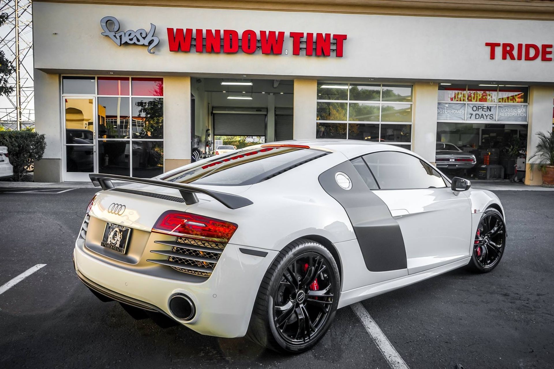 White Audi R8 with tinted windows parked outside a window tinting business.