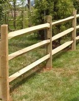 Wooden fence with wire mesh in a grassy yard, with trees and a stone path in the background