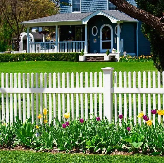 Blue house behind a white picket fence with colorful flowers in the foreground