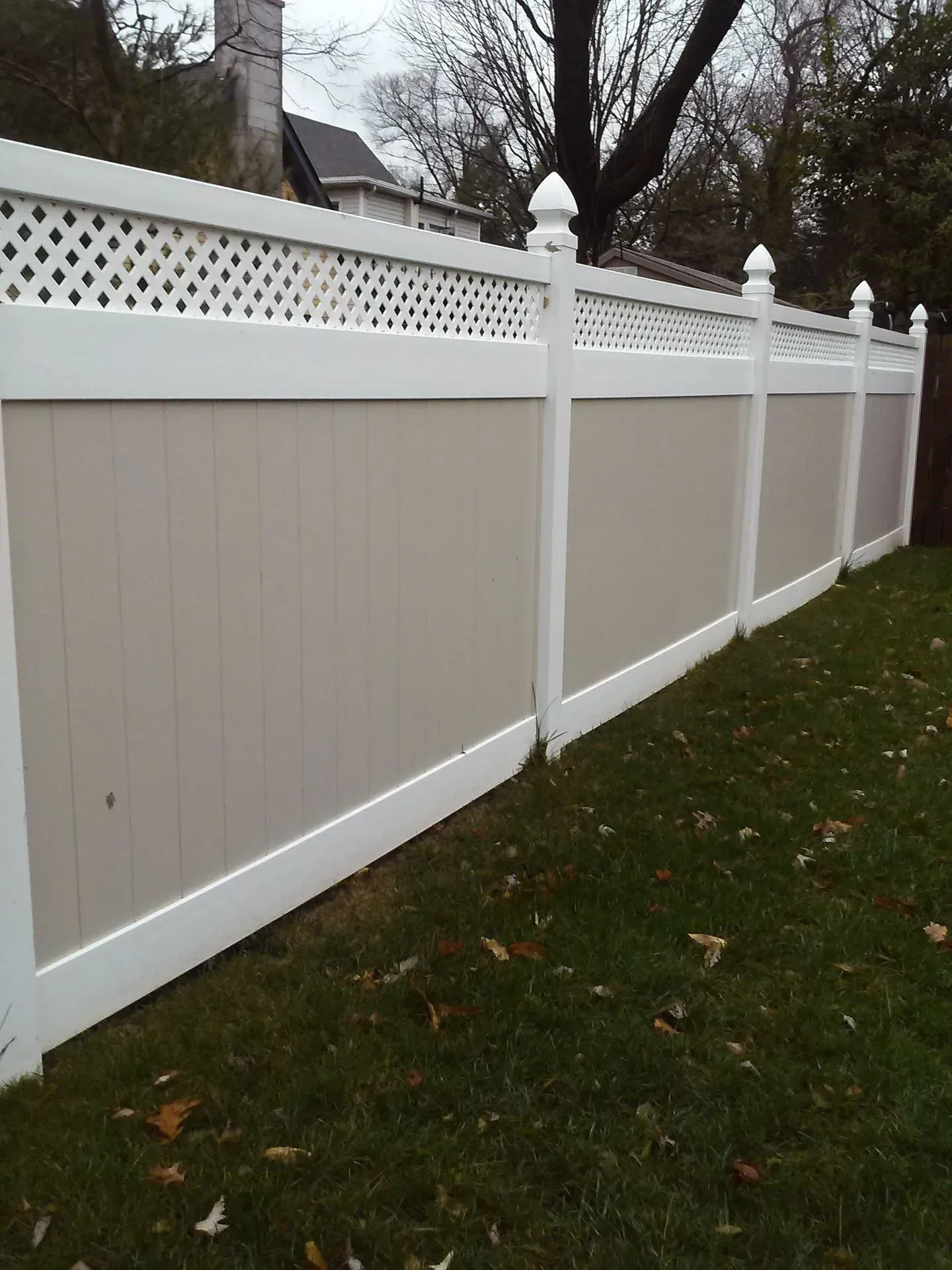 White vinyl privacy fence with lattice top along a grassy yard