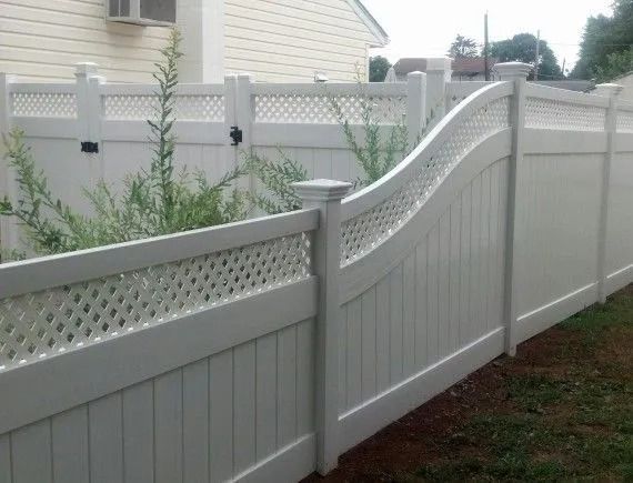 White vinyl fence with a decorative wave-top section in a suburban yard