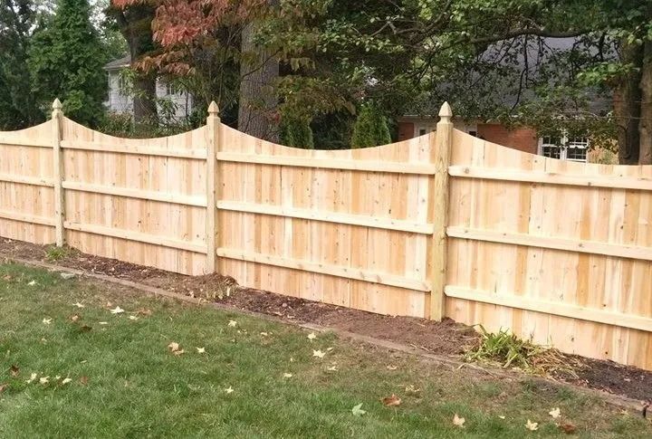 New light wood privacy fence along a grassy yard with trees in the background