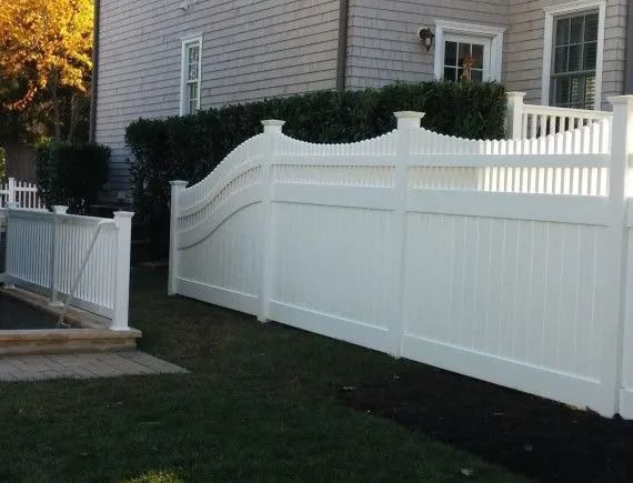 White vinyl privacy fence along a house and walkway in a backyard.