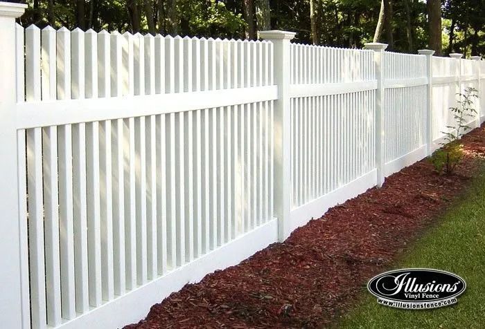 White vinyl picket fence along a landscaped yard with red mulch and greenery