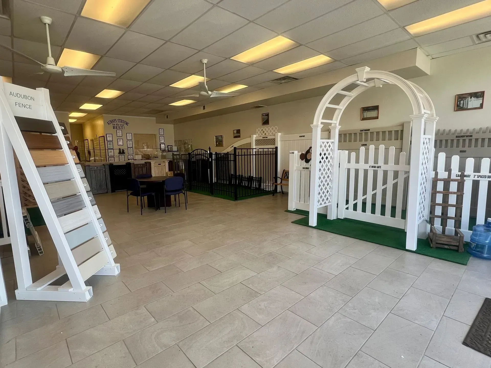 Bright showroom with white tile floor, shelves, and a white archway fence display inside a store.