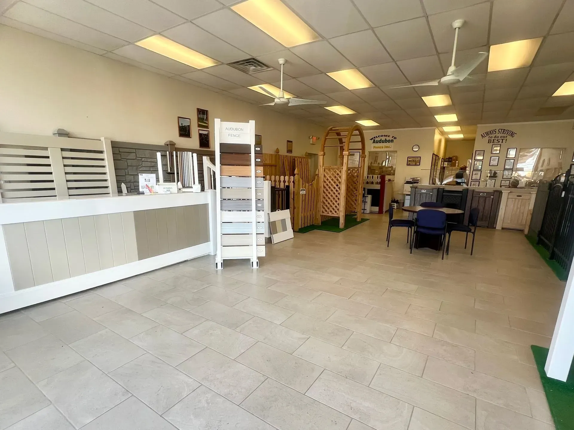 Empty retail showroom with tiled floor, white counters, and shelving under fluorescent lights.