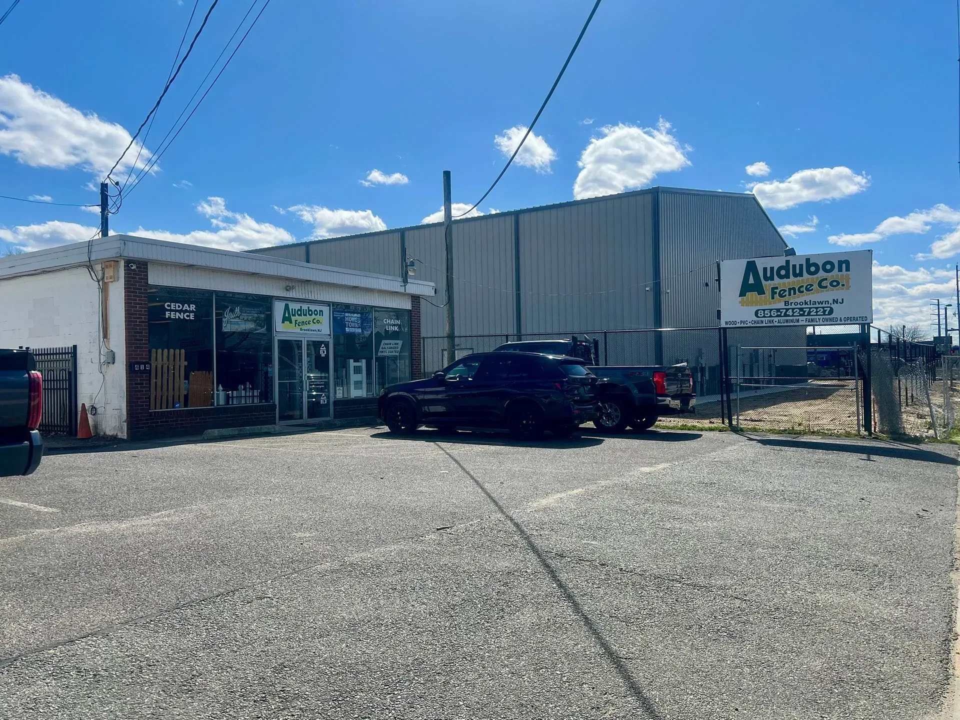 Small auto service building with a black SUV parked outside on a sunny day