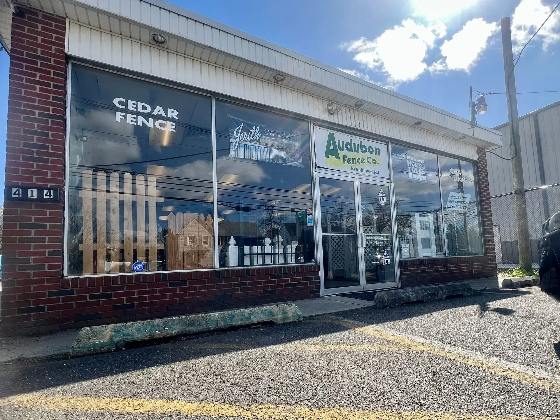 Storefront with “Cedar Fence” and “Airborne” signs, brick facade, and gravel parking area