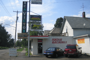 Two cars are parked in front of a store called rca victor