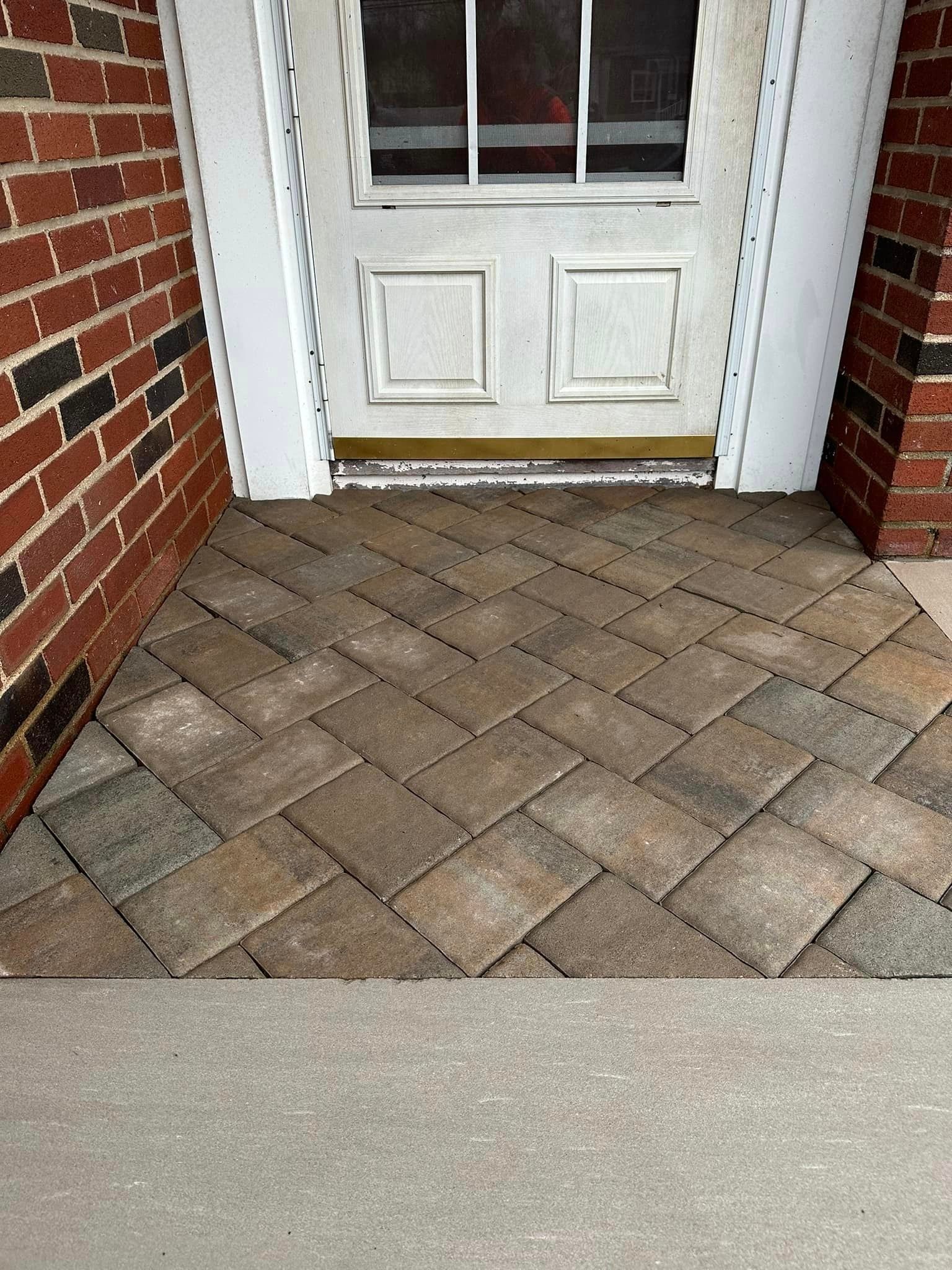 There is a brick walkway leading to the front door of a house.