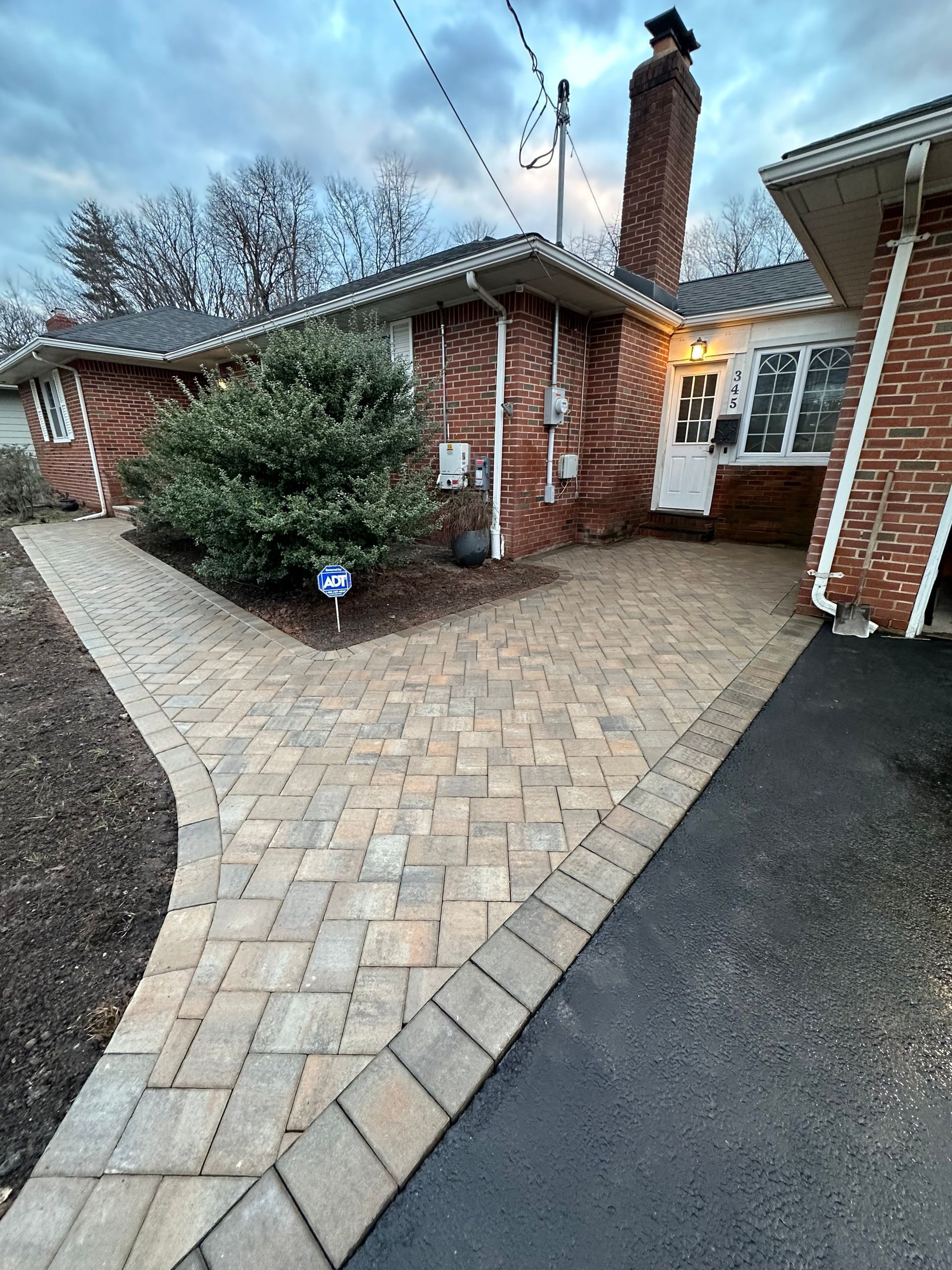 A brick house with a brick walkway leading to it.