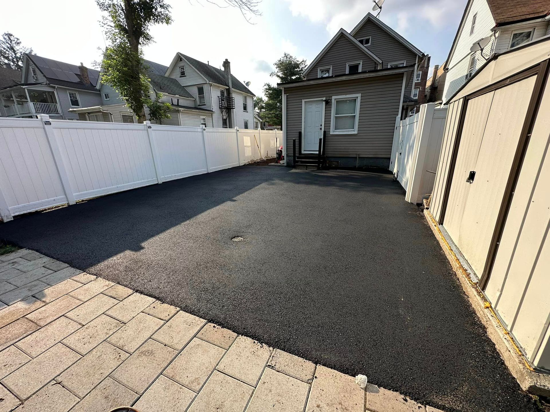 A driveway leading to a house with a white fence and a garage.
