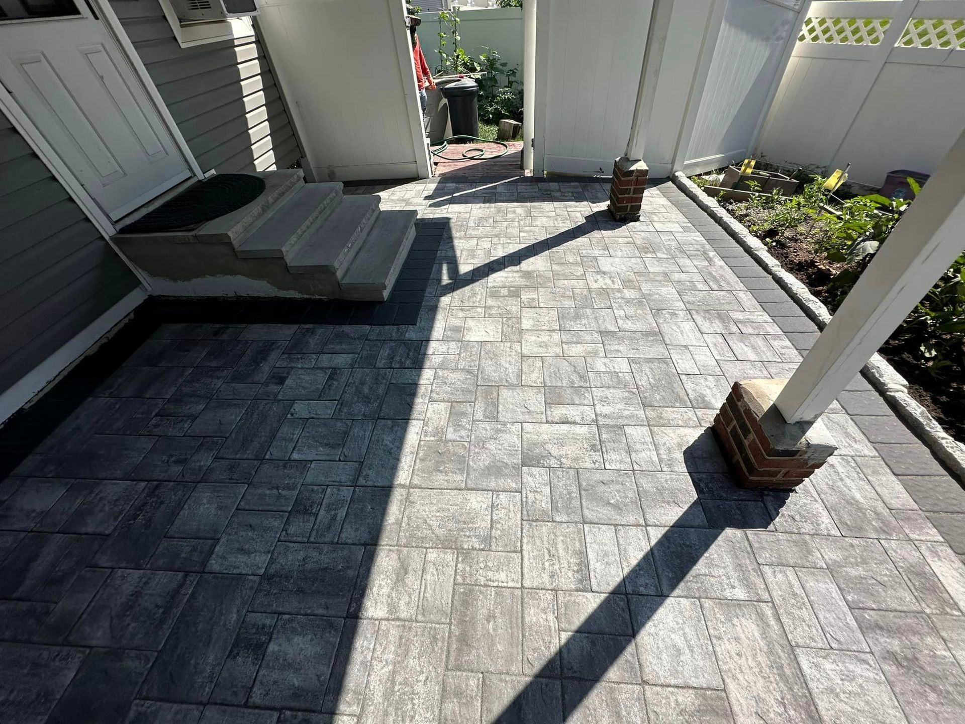 A patio with a hot tub and a fence in the background.