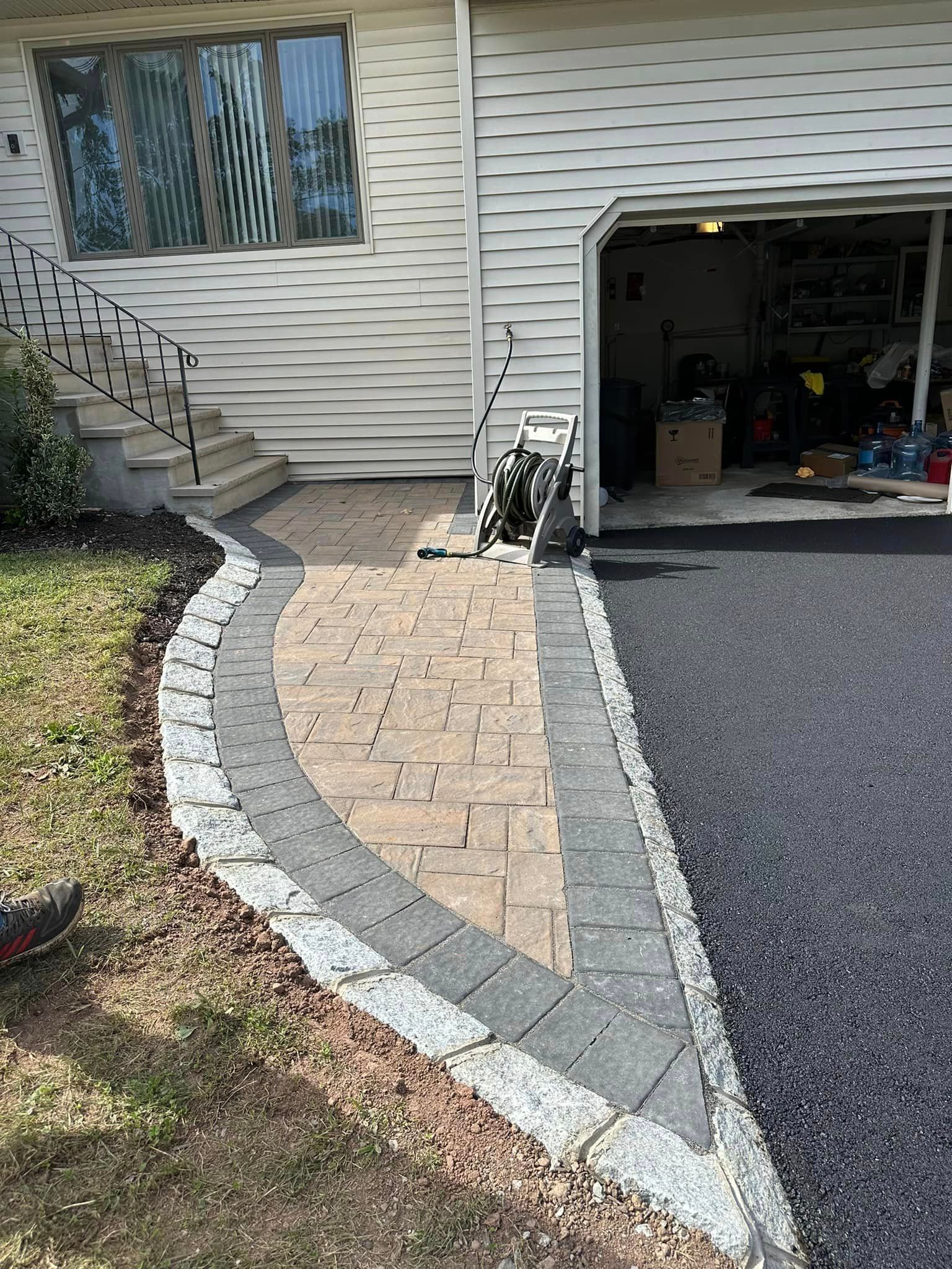 A brick walkway leading to a garage next to a house.