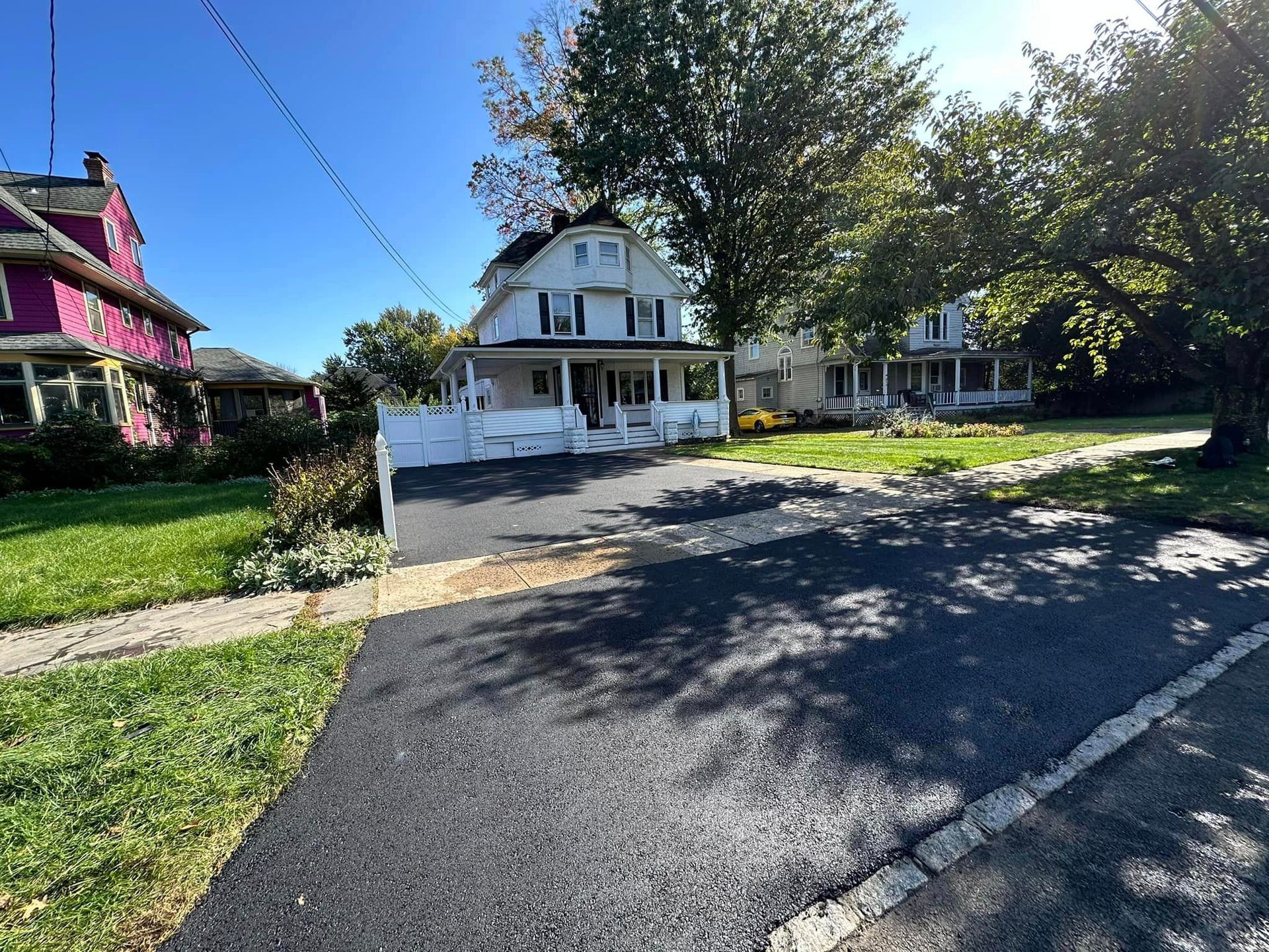 A driveway leading to a house with a purple house in the background