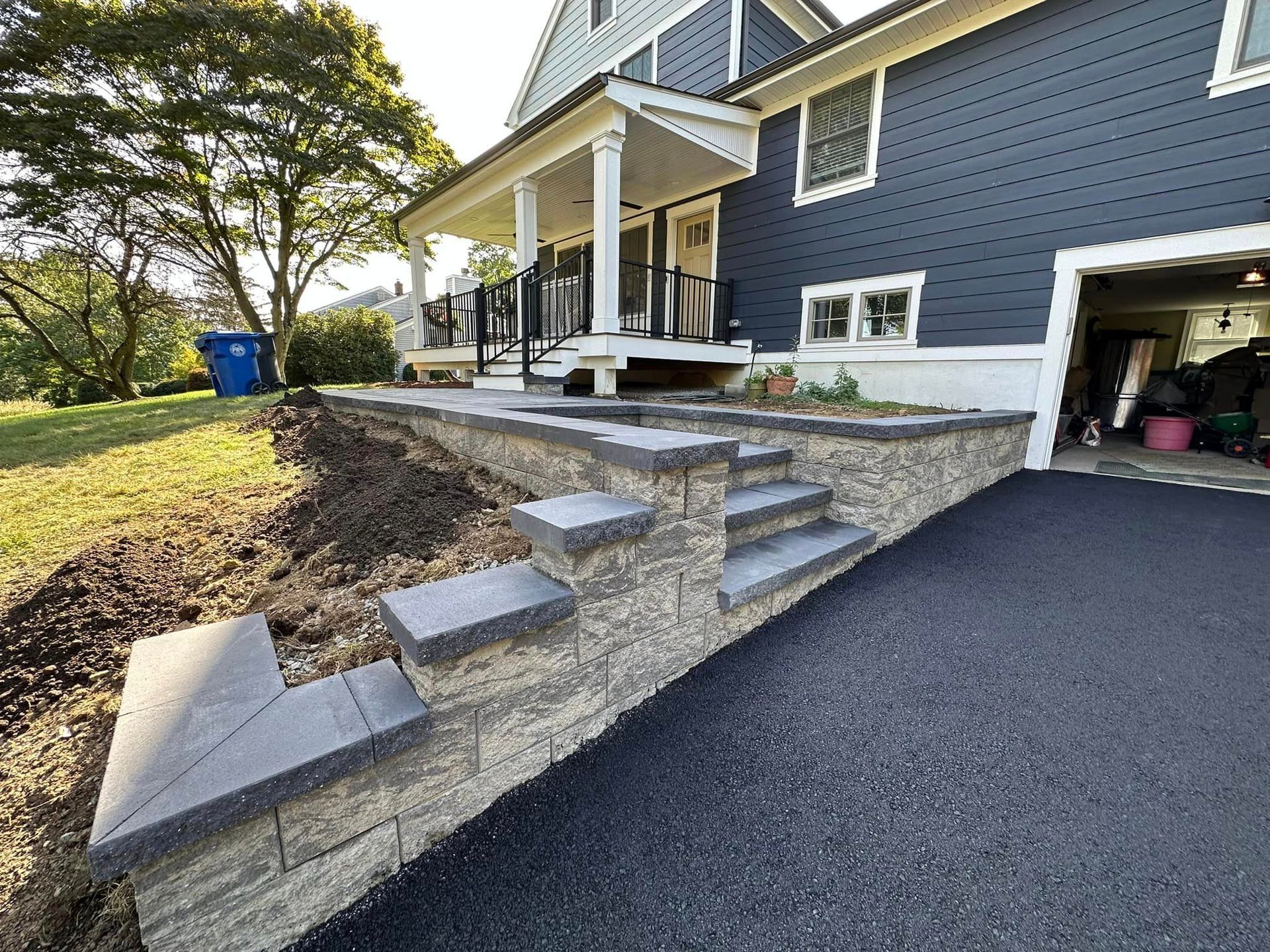A blue house with stairs leading up to it and a garage.