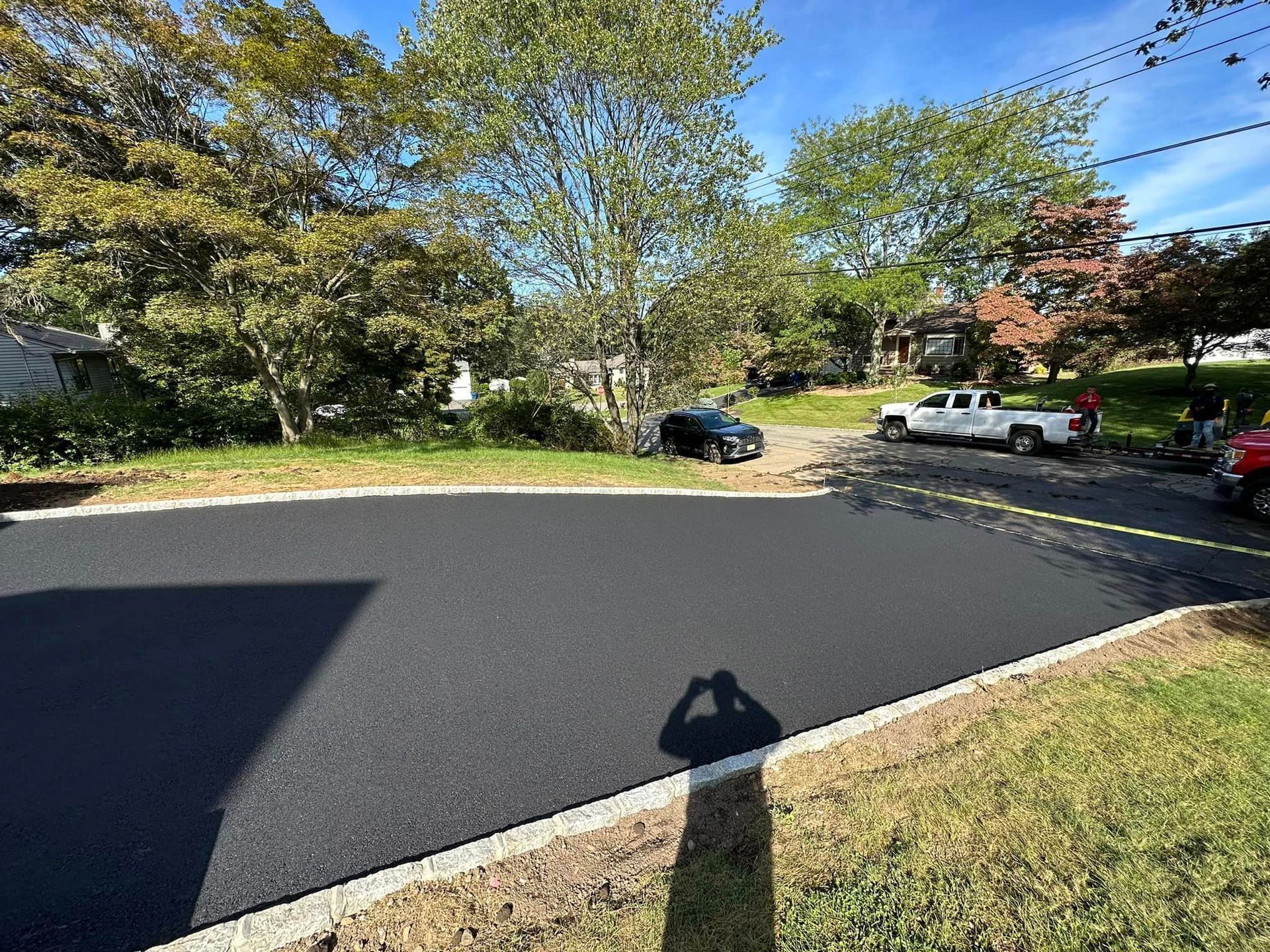 A shadow of a person is cast on a newly paved road.