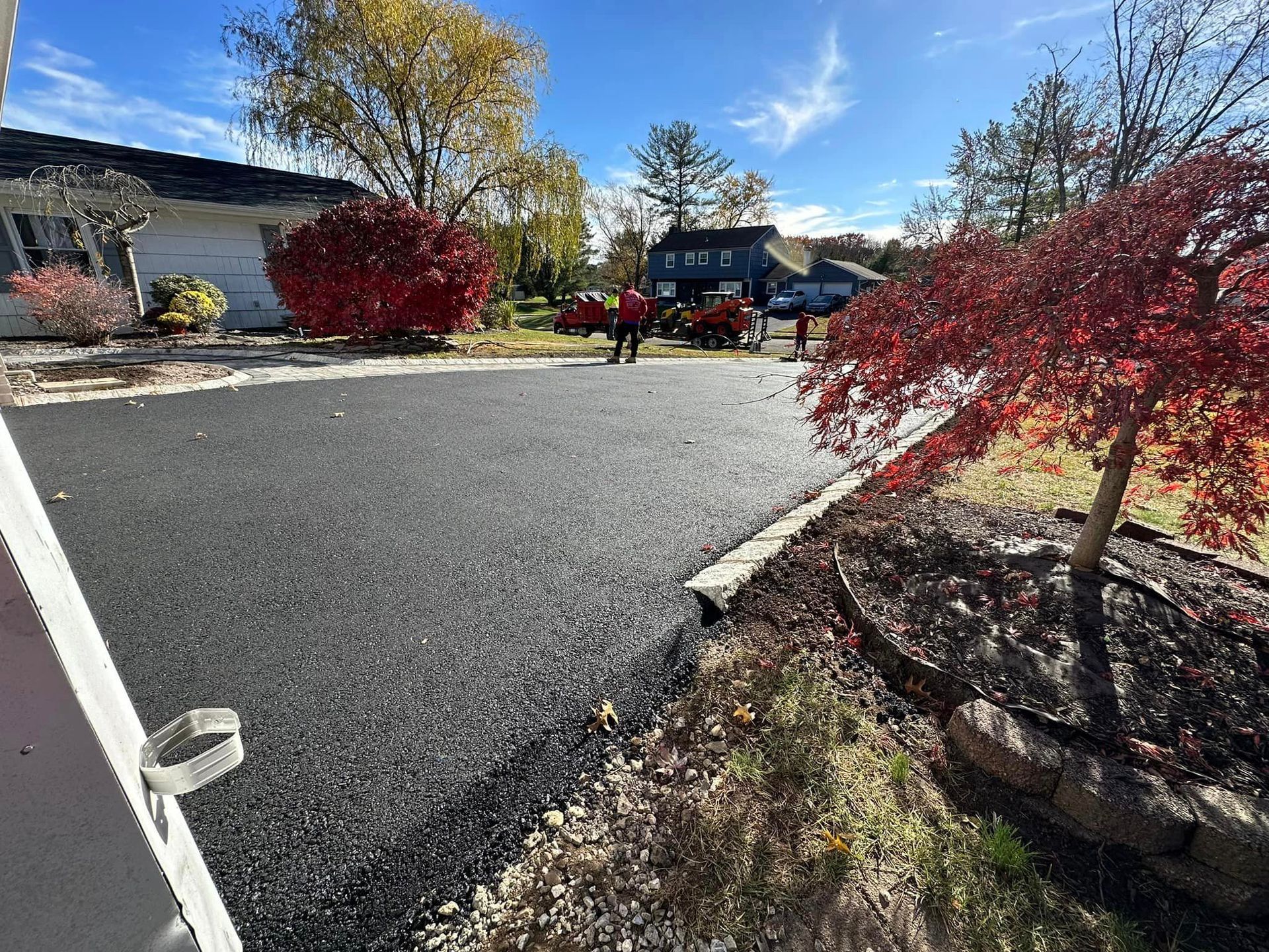 A person is walking down a driveway in front of a house.