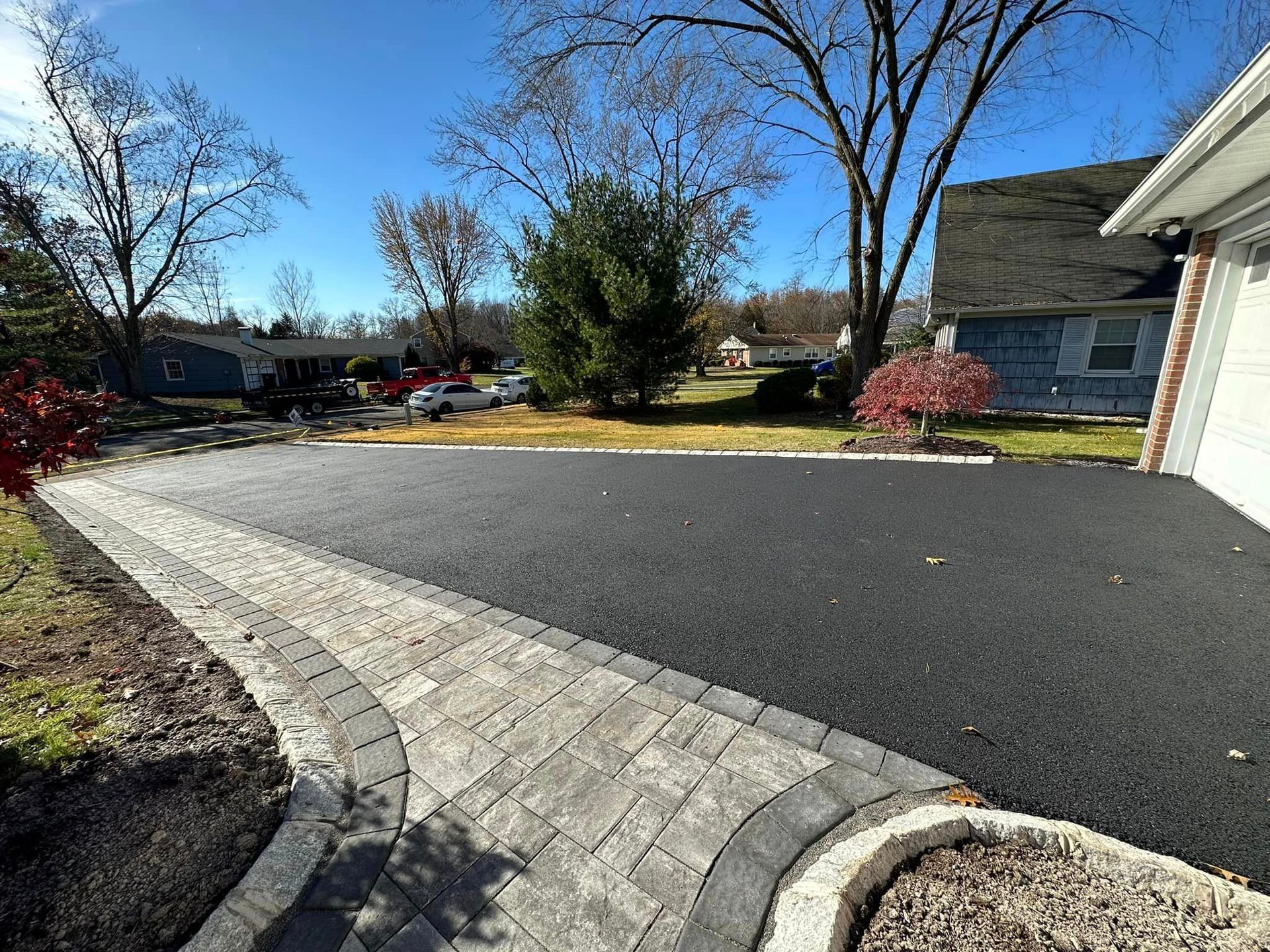 A driveway with a brick walkway leading to a house.