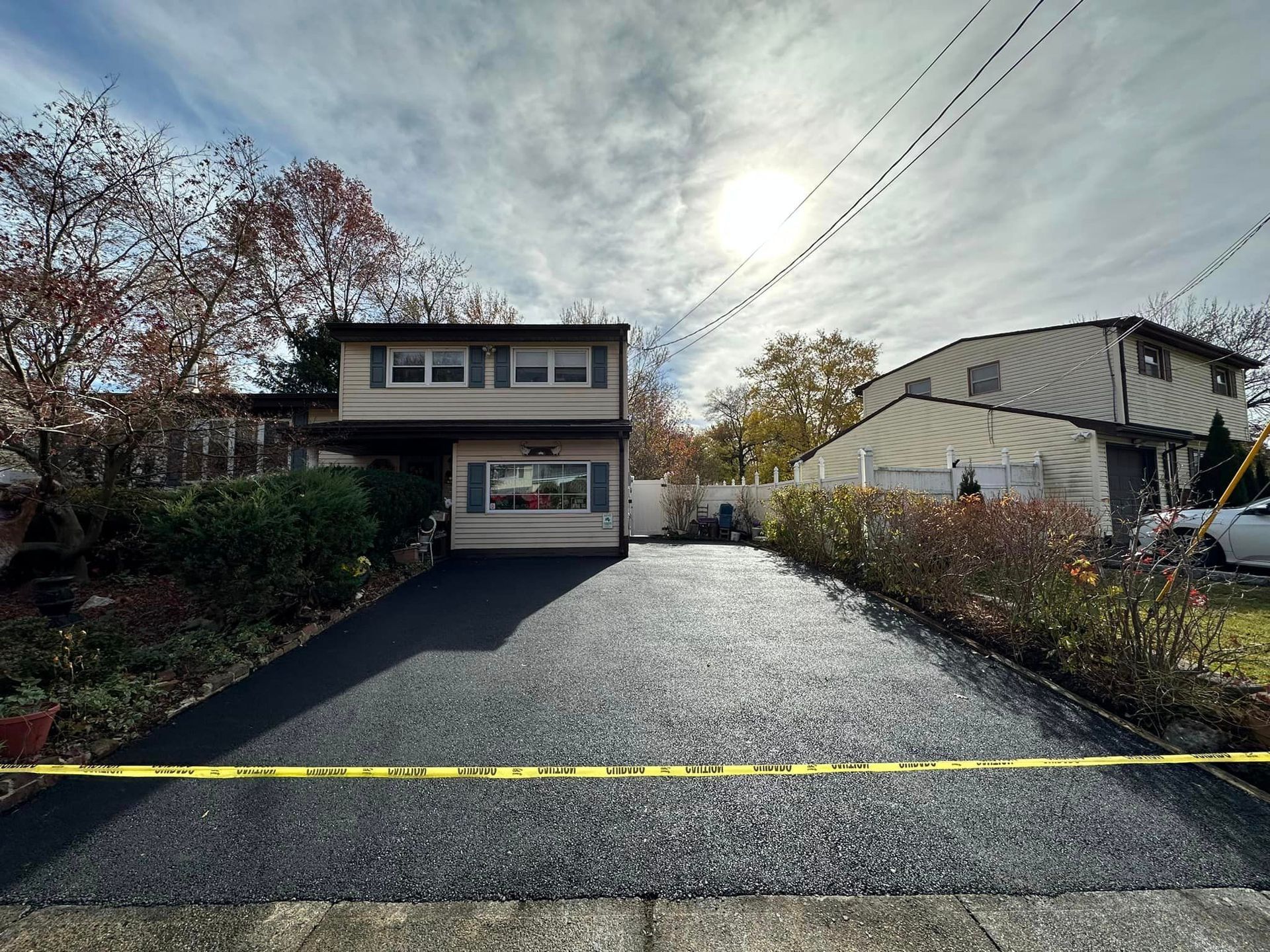 A driveway leading to a house with a yellow tape around it.
