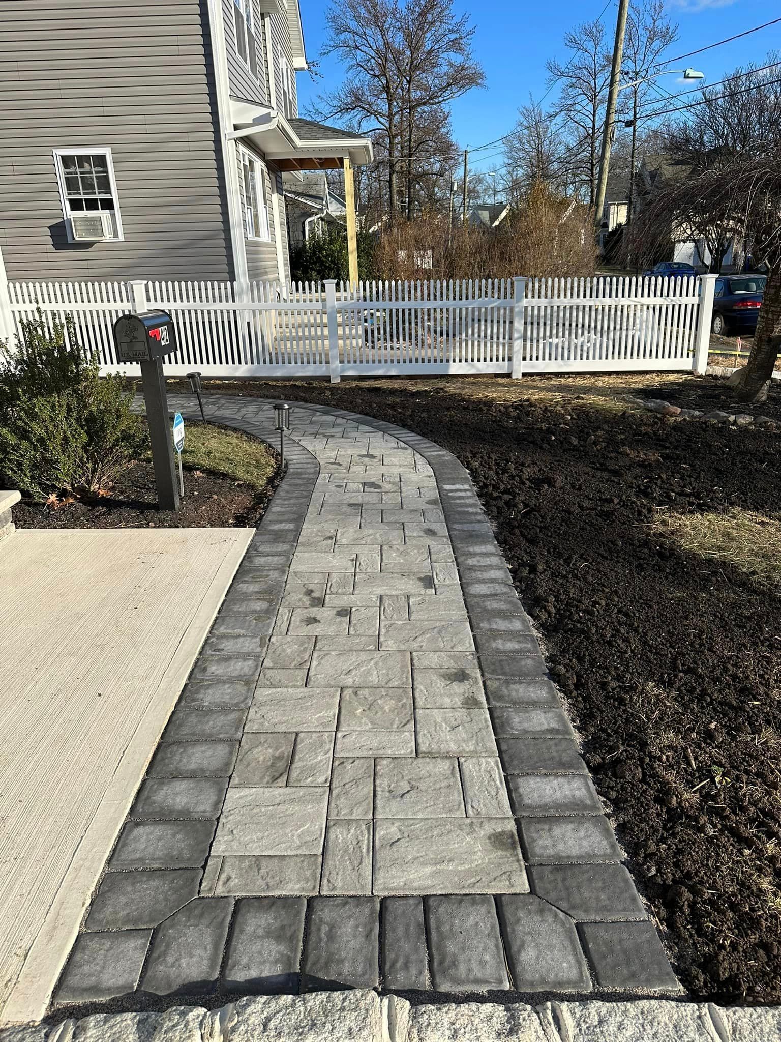 A walkway leading to a house with a white picket fence.