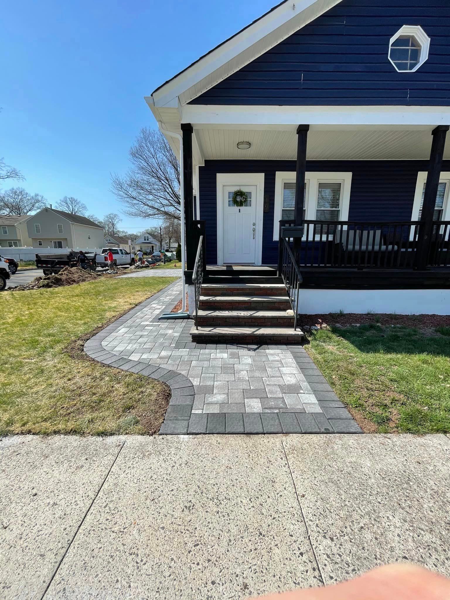 A blue house with a brick walkway leading to the front door.
