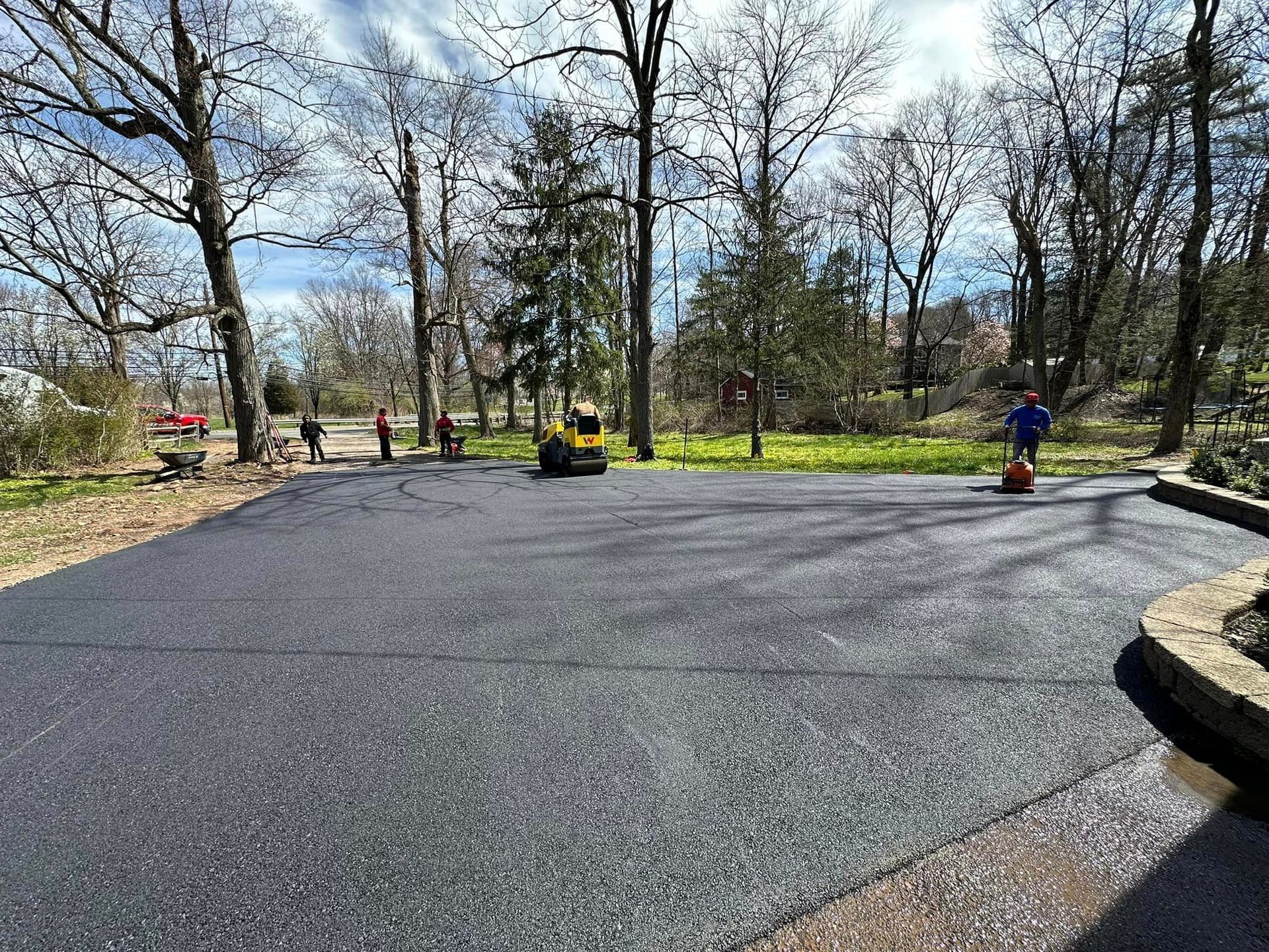 A group of people are working on a new asphalt driveway.