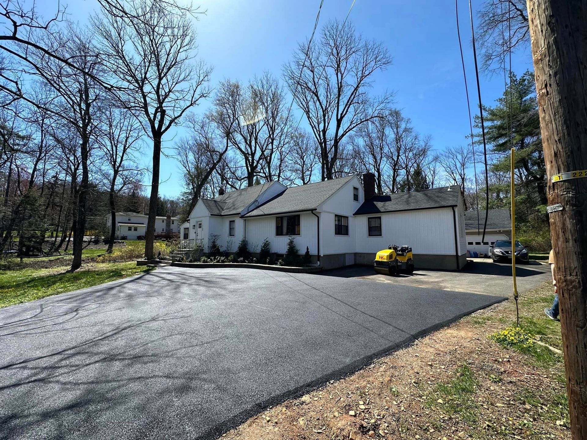 A white house is sitting on the side of a road surrounded by trees.