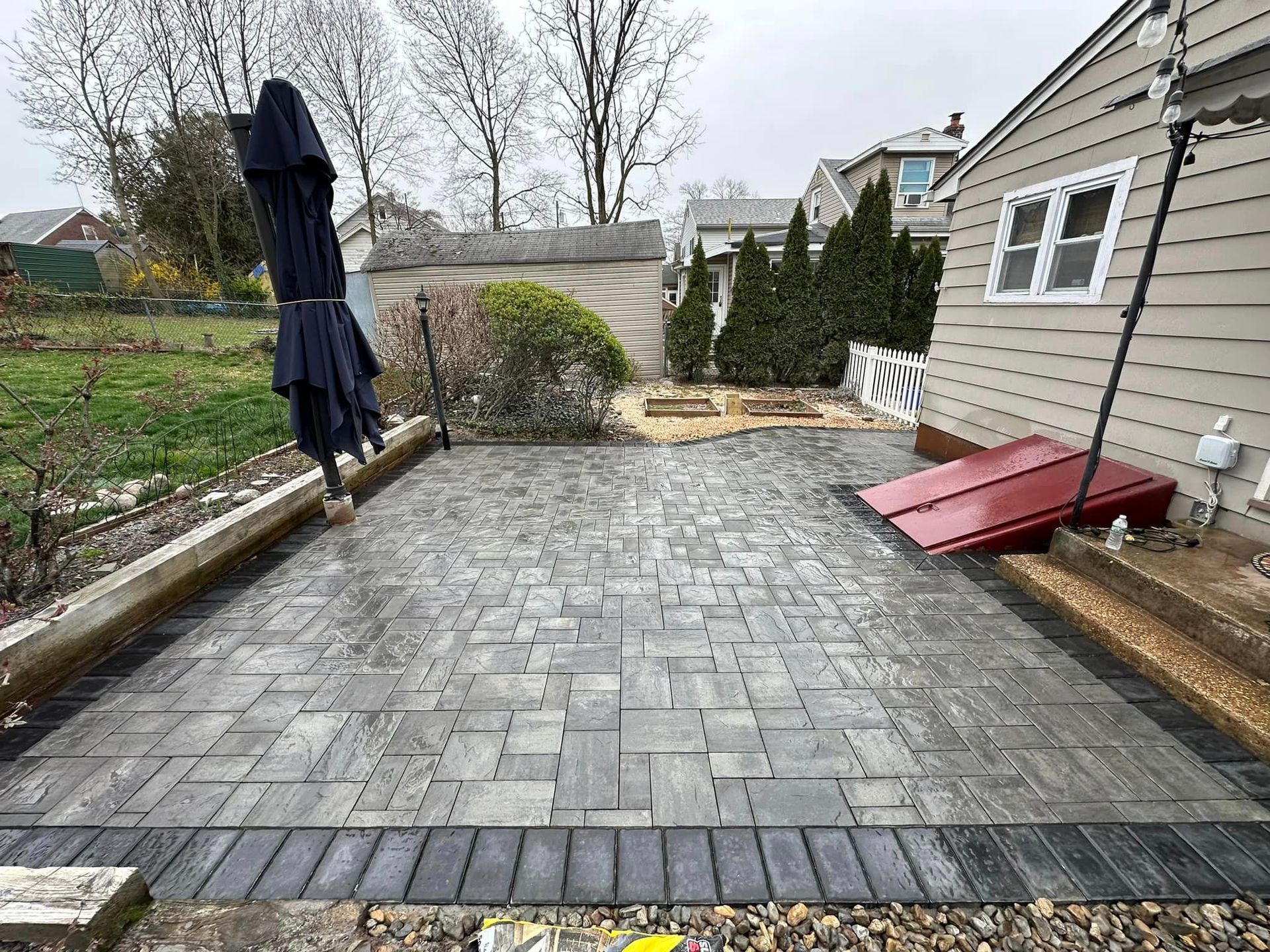 A patio with a blue umbrella in front of a house.