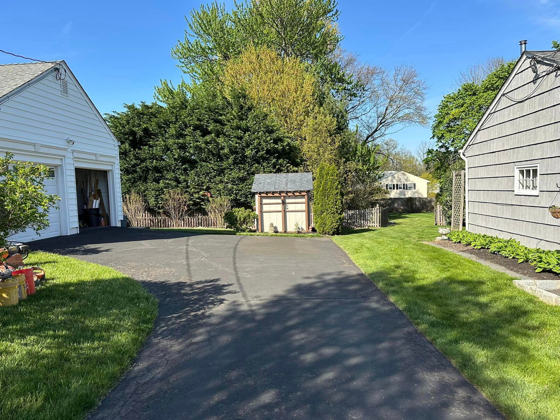 A driveway leading to a house with a garage and a shed.
