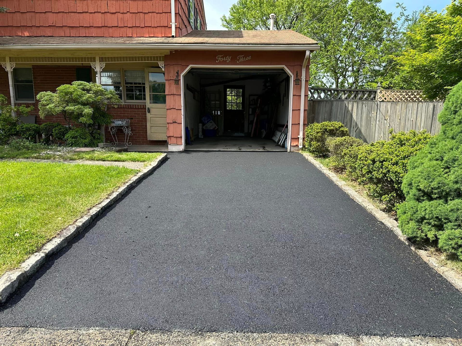 A driveway leading to a garage with a brick house in the background.