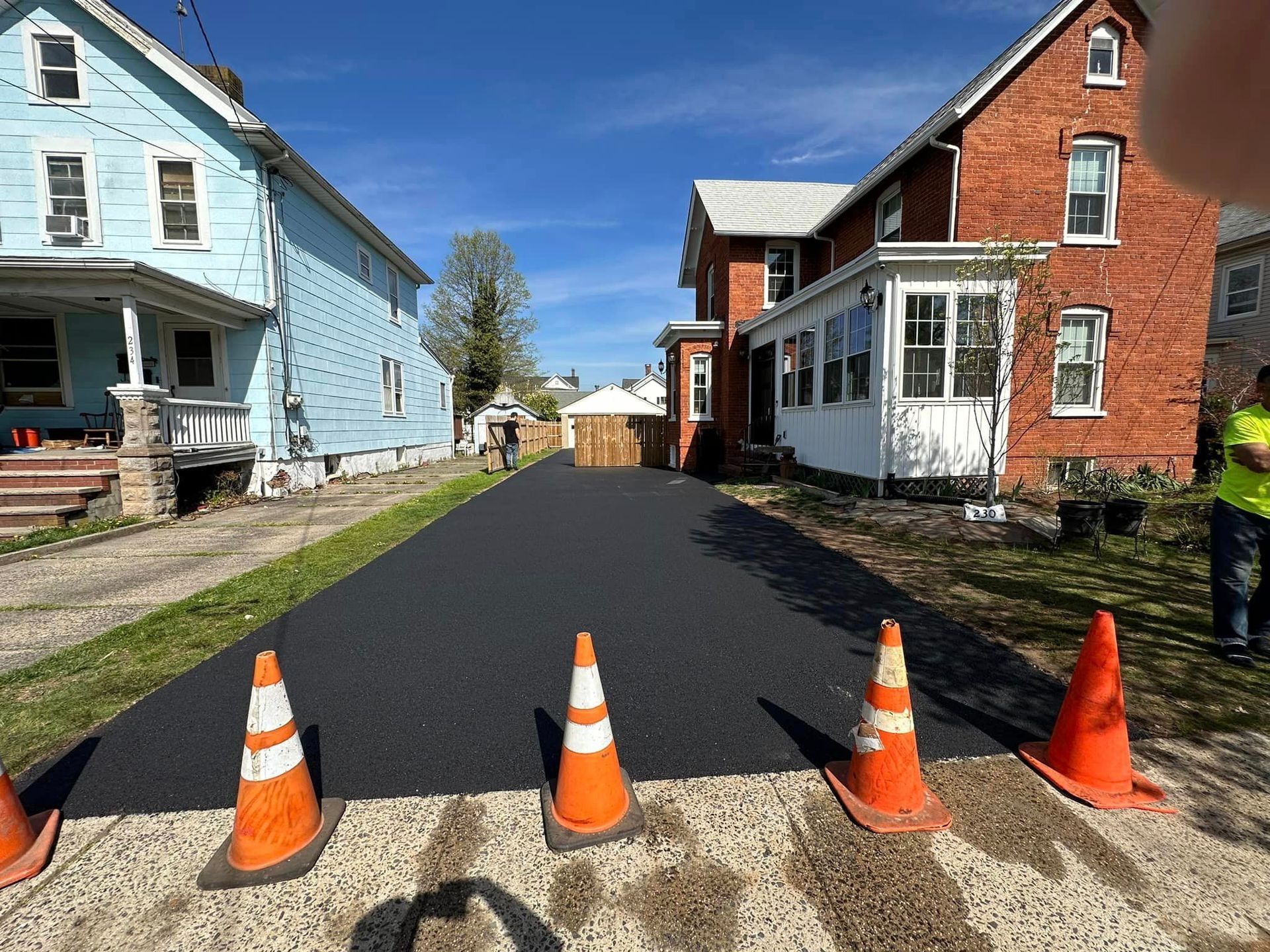 A row of orange and white traffic cones are sitting on the side of a road.