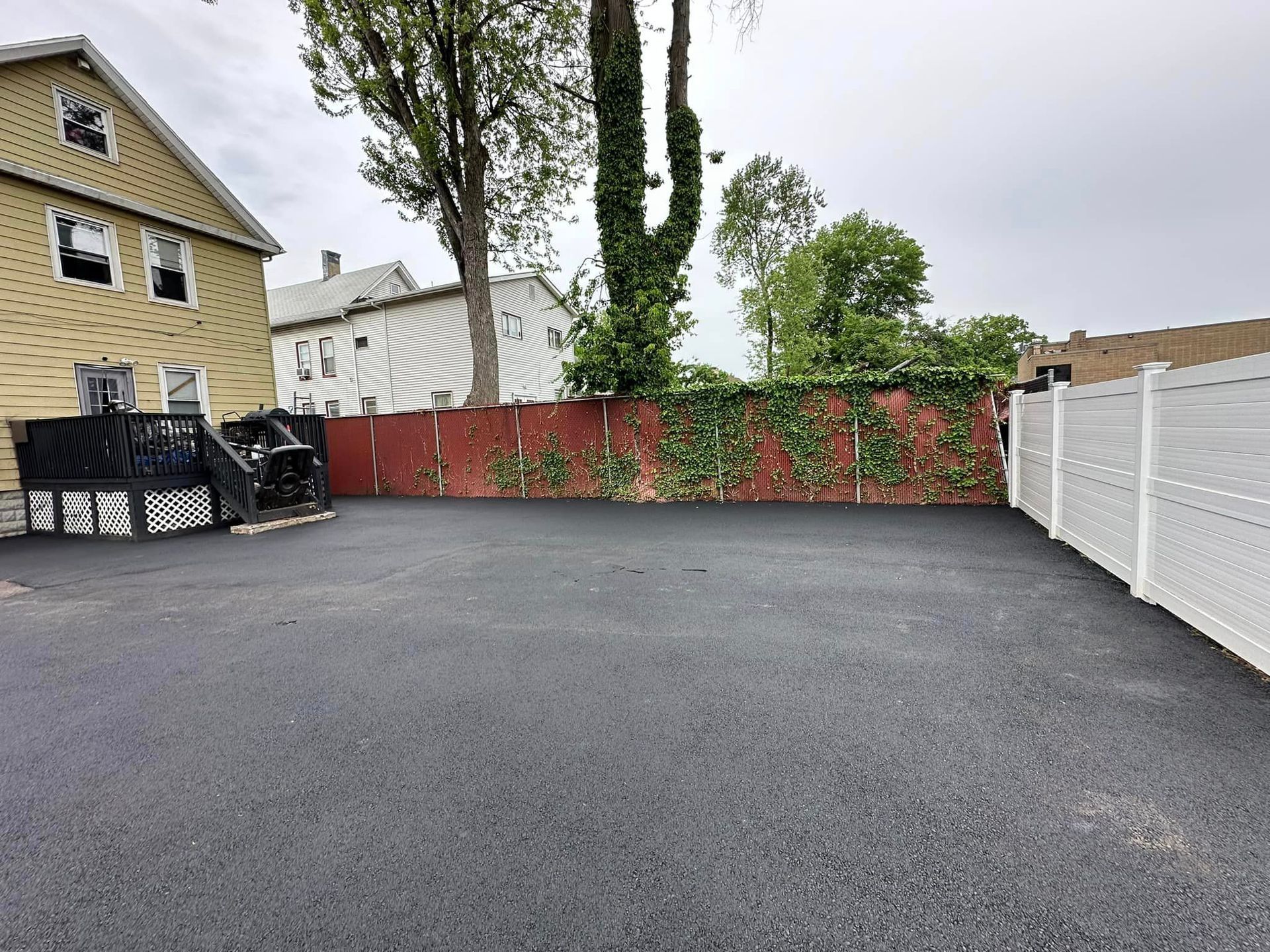A parking lot with a white fence and a yellow house in the background