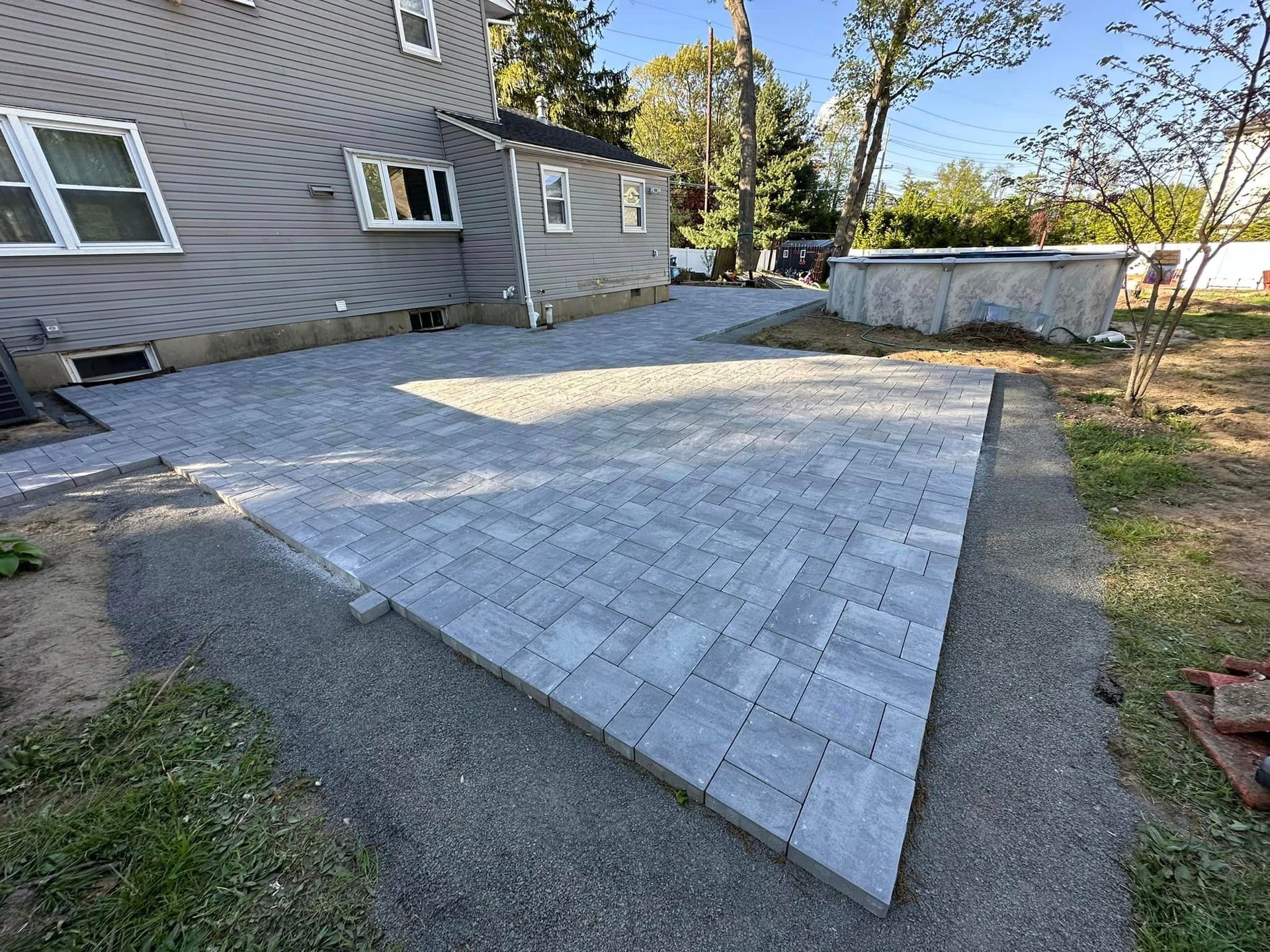 A brick driveway is being built in front of a house.