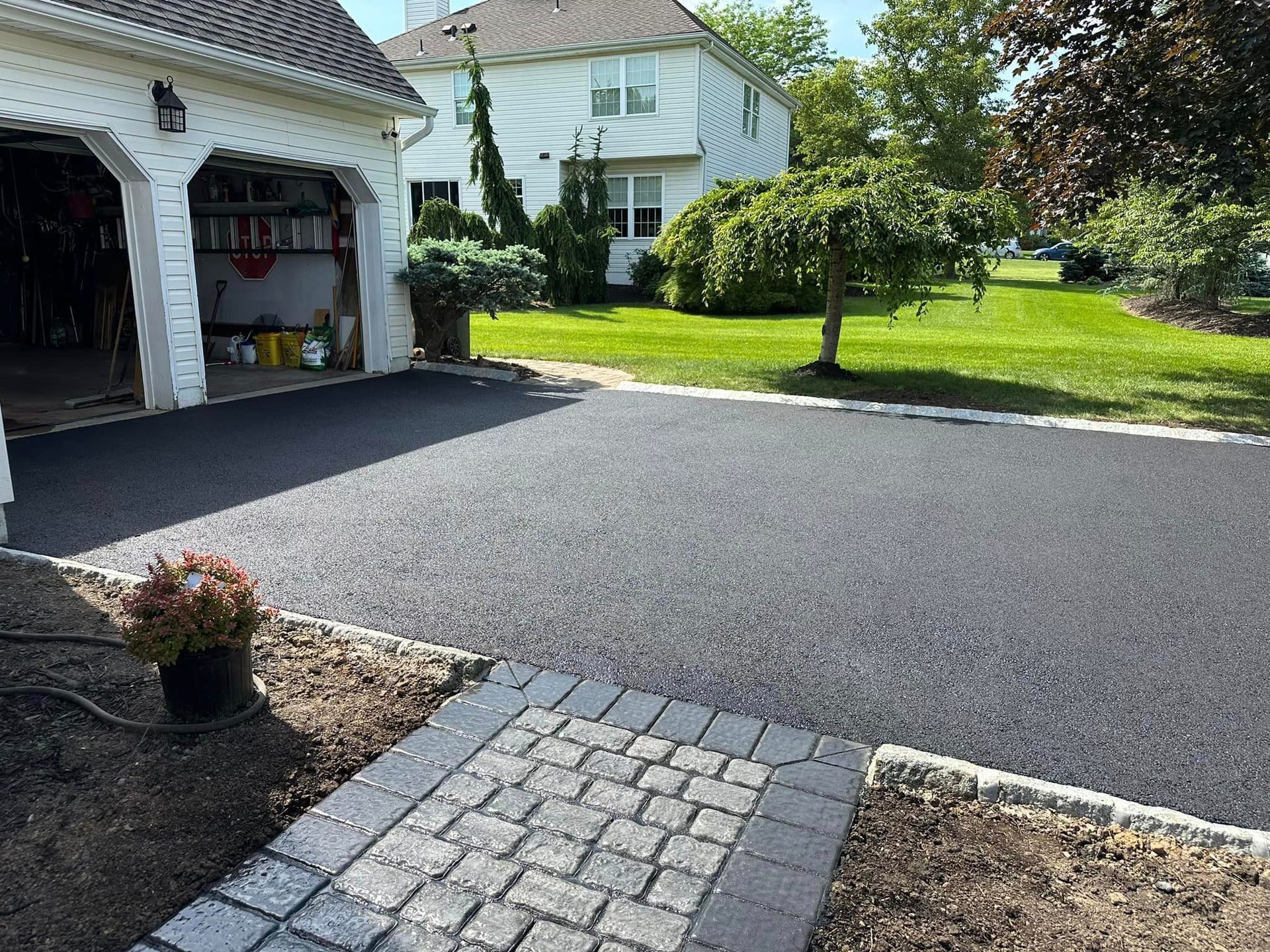 A driveway with a brick walkway leading to a garage and a house.