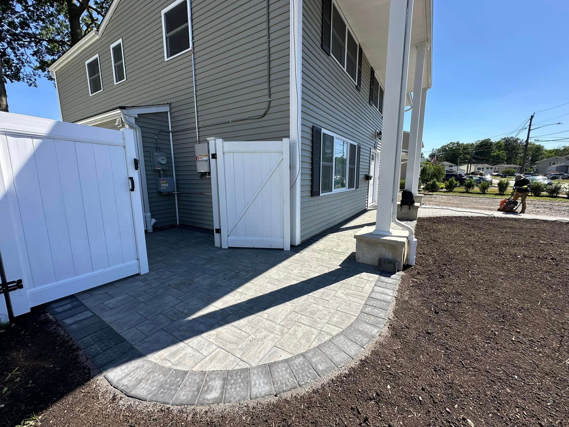 A house with a white fence and a patio in front of it.