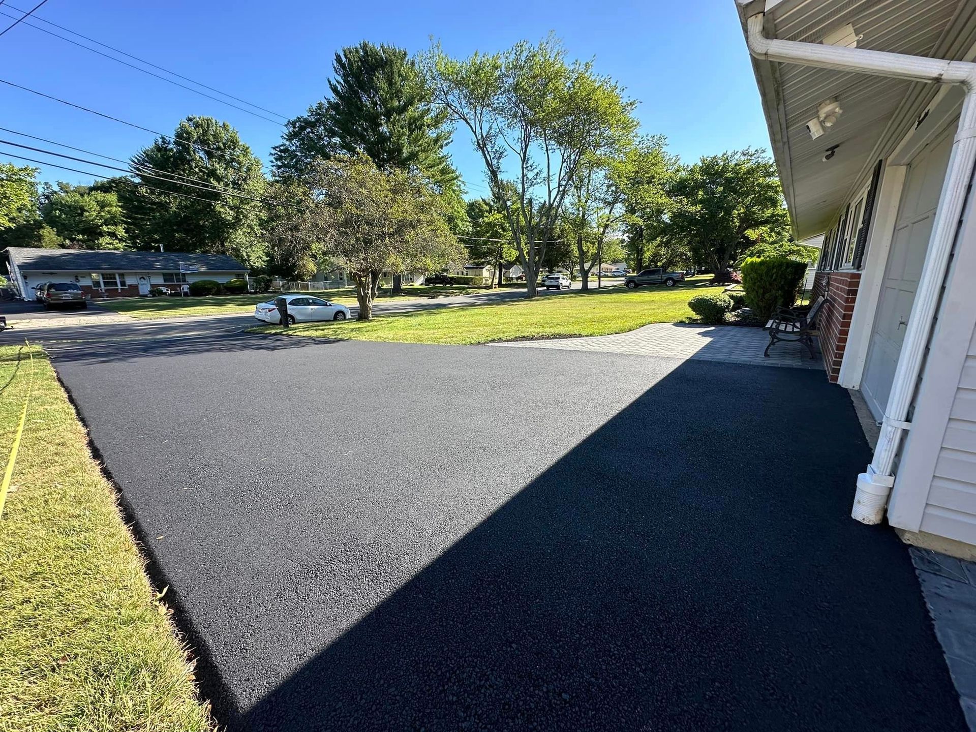A black driveway is being installed in front of a house.